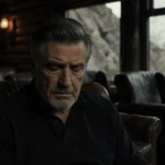 Alec Baldwin sits in a dim cabin with leather armchairs and a soft spotlight on his introspective gaze