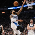 Anthony Davis drives toward the hoop with Dallas Mavericks jersey sponsor and teammate Luka Doncic watching behind.