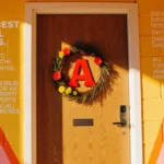 Wooden school door with a red A letterplate and bright flower wreath under warm sunlight symbolizing Arlington ISD progress