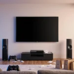 Living room showcases big screen TV with gaming consoles and sound system under warm lighting and shopping bags