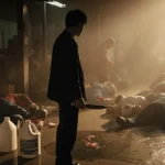 Man holding knife near bleach puddle with injured workers lying on the ground.