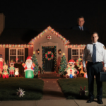 Homeowner stands guard with garish holiday lights and a disapproving HOA official nearby.