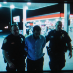 Nick Reiner being handcuffed by police with officers gripping him and neon glow from gas station