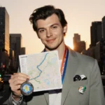 Harry Styles standing holding a marathon map with Tokyo skyline at sunset and warm golden light.