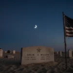 American flag standing with tattered folds beside memorial stone with names Edgar and William in desert dawn