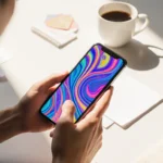 iPhone screen shows vibrant chat background with swirling patterns on a minimalist desk with coffee under warm natural light