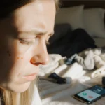 Meredith Thornton looks worried with morning light spilling over her face and a phone showing a missed call in the chaotic be