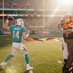 Quinn Ewers throws a pass with Tua Tagovailoa watching from the sidelines and autumn light on Hard Rock Stadium