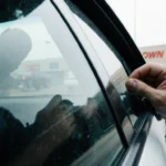 Suspect fleeing with hand clutching a bag while Dallas police car blocks a vehicle near LBJ Freeway Town East Mall backdrop.
