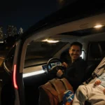 Waymo autonomous car glides through nighttime San Francisco streets with a stroller holding a newborn baby and a smiling driv