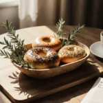 Fresh bagels arranged in wooden basket with steaming coffee and newspaper on breakfast table