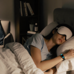 Woman lying in bed with Oura Ring and Manta Sleep Mask as sleep aid in soft warm light