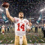 Brock Purdy celebrating victory with arm raised and 49ers logo visible near Eagles players on field