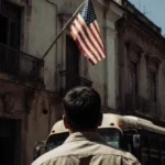 Bus driver standing with back to viewer and eyes looking upward with faded American flag behind in Caracas street