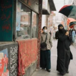 Person typing on laptop with coffee mug and books on desk showing study session