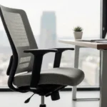 Ergonomic office chair sits at modern desk with laptop and potted plant near sunlit window