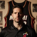Erik Spoelstra stands before a Miami Heat jersey with vintage memorabilia and nostalgic photos showing his coaching journey