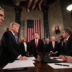 Lawmakers debating the funding bill with papers and laptops at desks and the flag above in dim light in the Capitol