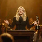Chelsea Handler addressing a packed audience with her hands holding a microphone and a faint Critics Choice Awards statuette