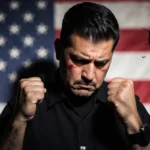 Capitol Police Sgt. Gonell stands with clenched fists against a blurred American flag and a broken clock in city shadows