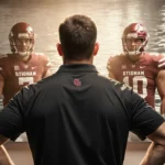 Football coach stands with hands on hips in locker room mirror with quarterback reflections showing determined expressions an