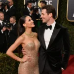 TV star posing on red carpet with handsome date and golden Globes backdrop showing elegant gowns