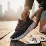 Happy shopper holds up new Hoka shoes with shopping bag and coupons on wooden floor