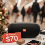 JBL Charge 6 speaker placed on a desk with a bright red price tag highlighting a $70 discount with shoppers browsing behind.