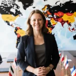 Confident woman stands before global conference table with country flags and world map showing cybersecurity leadership