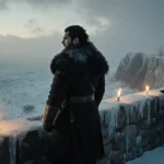 Jon Snow stands atop the frozen wall with Arya approaching in the distance and golden torchlight flickering across the ice