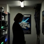 Kathleen Kennedy stands thoughtfully in dim corridor with Star Wars props and memorabilia lining the walls