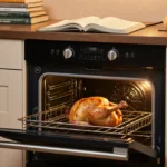 Oven glowing warmly with roasted chicken inside and cookbooks stacked nearby creating cozy kitchen scene