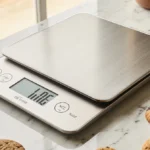 Kitchen scale showing weight with cookies arranged around it under warm natural light