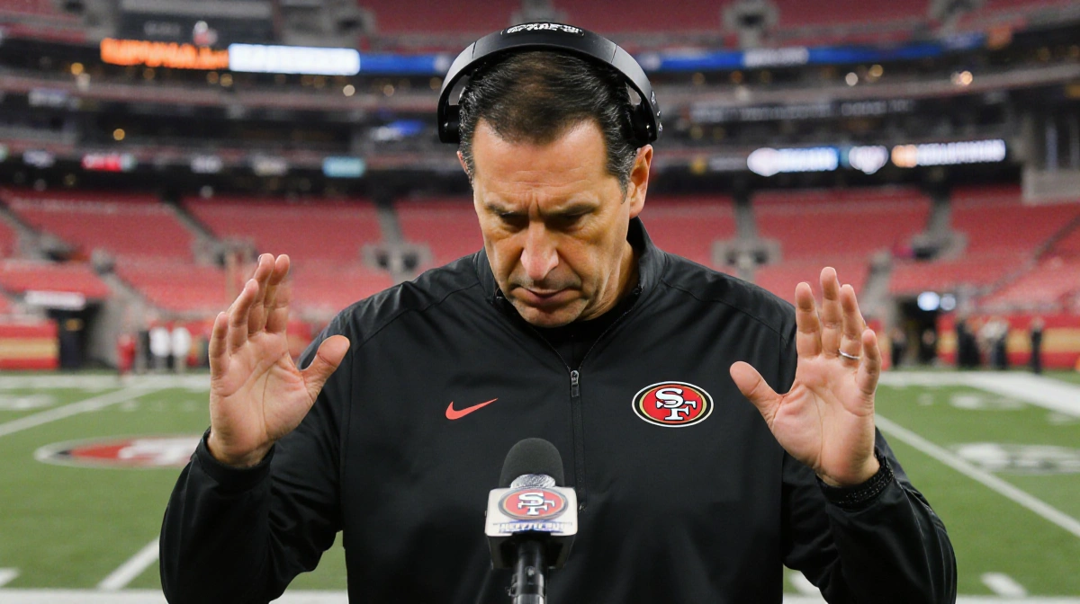 Kyle Shanahan speaking at press conference with solemn expression and gesturing hands about George Kittle injury