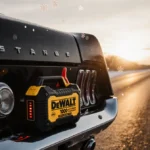 Vintage muscle car parked on snow road with jump starter glowing under sunrise sky and frosty flakes and morning sun