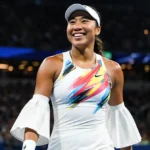 Naomi Osaka walking toward camera Australian Open with tennis dress and metallic sleeve and lights reflecting on her face