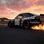 NASCAR number 88 Toyota racing around track at sunset with flames and smoke from tires and The Chase on sidepod