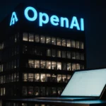 OpenAI headquarters glows at night with electric blue logo above while a laptop on table shows faint screen light