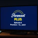 Television screen glowing with Paramount Plus logo and episode 8 details at midnight in front of a blurred cityscape