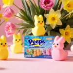 Colorful marshmallow Peeps chicks scatter across pink desk with fresh tulips and Easter eggs adding spring cheer
