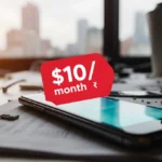 Mobile phone on desk showing red $10/month price sticker with $25/month rate below and blurred city background