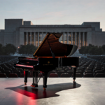 Piano reflects stage lights with empty seats and Kennedy Center silhouette in background