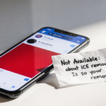 Folded note placed on blurred smartphone screen showing redacted social media feed with Not Available symbol