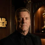 Stellan Skarsgård stands proudly with Golden Globe trophy in hand and Star Wars logo glowing behind him