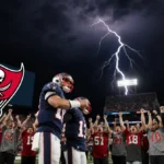 Tom Brady stands confidently beside teammate with Buccaneers logo on Jumbotron amid cheering fans at night