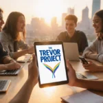 Young adults collaborating around table with Trevor Project logo on tablet and sunset cityscape behind