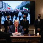 President Trump sits at wooden desk with advisors watching Tehran protest footage on screen
