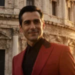 Valentino Garavani stands in red suit with Roman villa behind him and sunset glow on his face