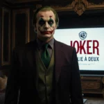 Warner Bros executive stands before Joker Folie à Deux logo with dramatic lighting and gold room showing smug expression