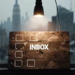 Wordle puzzle board glows with warm lamp light showing five empty boxes and faint INBOX outline against foggy city backdrop.